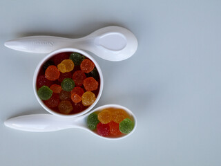 Sweet mixed color jelly candy in a white spoon against white background with copy space