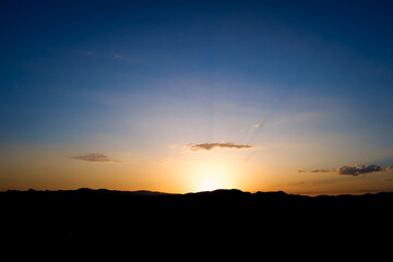 Beautiful sunset behind the mountains with the dark sky and romantic atmosphere.