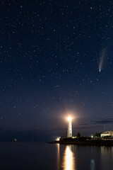 Vertical Panoramic HDR photo of Neowise comet over white Lighthouse at night sky