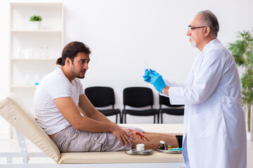 Obraz premium Leg injured man visiting old doctor in first aid concept