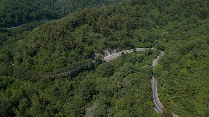 Aerial view from drone of curve road with a car on the mountain with green forest in Russia