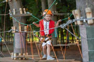 Cute preschool girl, active leisure, play area, overcoming obstacles on the playground in adventure...