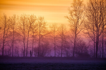 Landschaftspanorama mit Farbigen Verläufen beim Sonnenaufgang mit einer Silhouette eines Fußgängers im Gegenlicht - Lila Rot, Orange Gelb