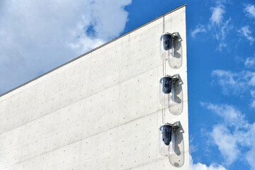 Flask-like street lamps on a concrete facade