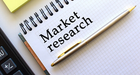 Notepad with text MARKET RESEARCH, next to it lies a calculator and yellow note papers. Business concept.