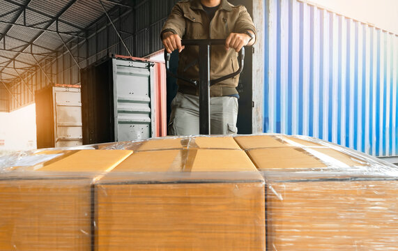 Worker unloading cargo shipment goods. package box, his using hand pallet jack load into a truck, Road freight transport, Warehouse industrial delivery shipment and logistics
