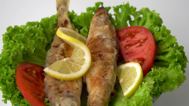 Osmerus eperlanus. Fried fish with lettuce, lemon and tomatoes. 
