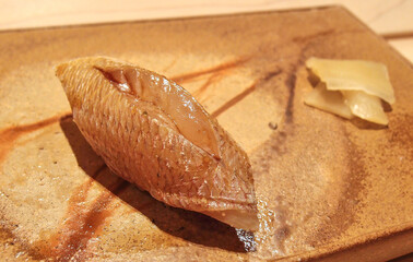 A piece of sea bream sushi on a beautiful pottery at a high class sushi restaurant in Ginza, Tokyo, Japan.