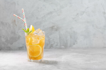 Lemon ice tea on concrete gray background with mint and ice with copy space
