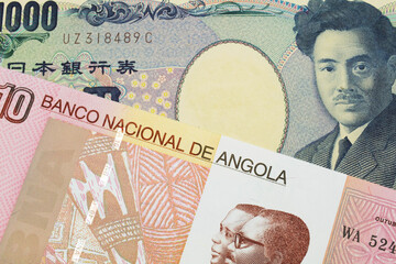 A macro image of a Japanese thousand yen note paired up with a colorful ten kwanza bank note from Angola.  Shot close up in macro.