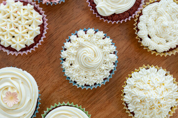 Home baked cupcakes beautifully decorated with buttercream on top placed on wooden table.