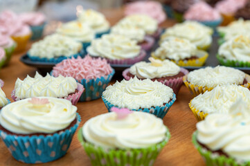 Home baked cupcakes beautifully decorated with buttercream on top placed on wooden table.