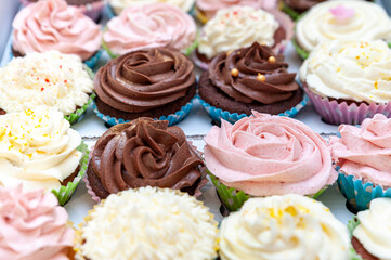 Home baked cupcakes beautifully decorated with buttercream on top placed on wooden table.