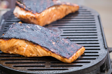 Fresh Salmon steak cooking on iron grates over flaming charcoal skin side up