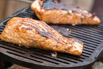 Fresh Salmon steak cooking on iron grates over flaming charcoal 