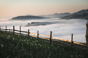 Beautiful colorful sunrise with cloud inversion and sunrays over the mountains and meadow with...