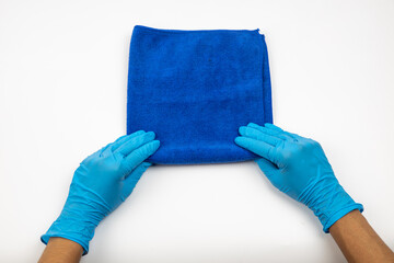 Close up of hands in rubber protective blue gloves cleaning the blue surface with a rag. Home, housekeeping concept
