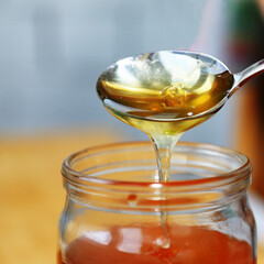 Thick honey drips from the spoon. 