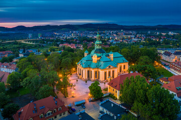 Aerial view of baroque church temple in the heart of Karkonosze mountains in Jelenia Gora surrounded by old city architecture at beautiful sunset. Photo taken from drone. Popular tourist destination