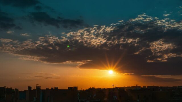 Timelapse of sunset over Vallecas city with few clouds in the sky and orange teal tones.