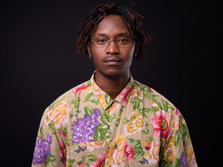 Young African man with dreadlocks against black background