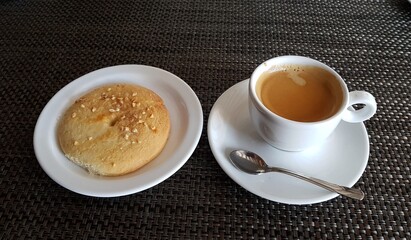 Cup of black aromatic coffee and cake on a saucer are prepared for breakfast