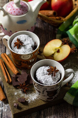 Autumn apple pie mugcake with red apples and spices on a rustic background.