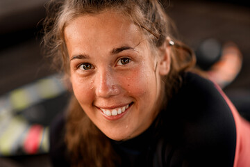 Fototapeta na wymiar Portrait of young cheerful woman with brown color eyes in black wetsuit.