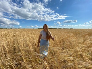 beautiful woman walks in a field with ears, takes pictures in a wheat field
