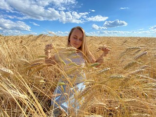 beautiful woman walks in a field with ears, takes pictures in a wheat field
