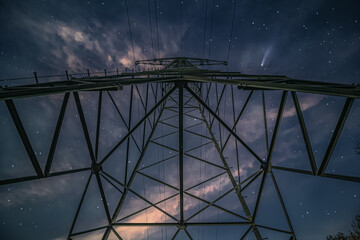 High-voltage mast, steel lattice mast for the transmission of electrical energy at night, with stars and comet in the sky
