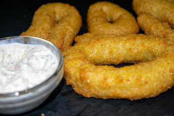 Onion rings and a glass saucepan with sauce. Close up.