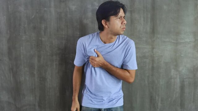Young asian man with chest pain on a gray background, Problems and health care concepts