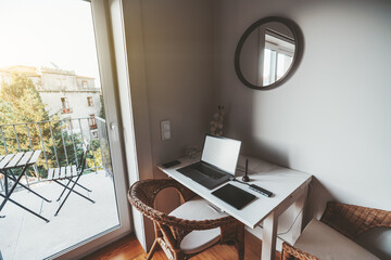A hispanic woman entrepreneur with a digital tablet in her hands is watching on the screen of the laptop of her colleague businessman sitting near to her on the sofa in a cozy office coworking area