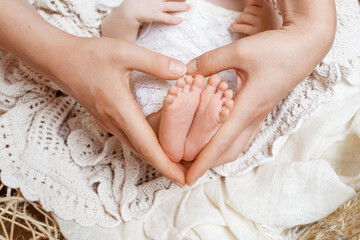 Obraz na płótnie Canvas Parent holding in the hands feet of newborn baby. Tiny newborn baby's feet on heart hands closeup. Mom and her child. Happy Family concept. Beautiful conceptual image of maternity. Copy space