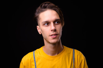 Young handsome rebellious man against black background