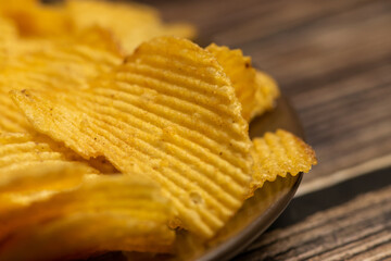Fluted potato chips on a wooden background. Close up.