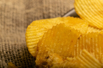 Fluted potato chips on a background of homespun fabric with a rough texture. Close up.