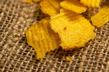 Fluted potato chips on a background of homespun fabric with a rough texture. Close up.