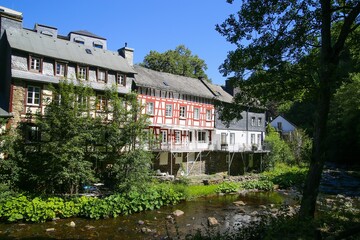 Fototapeta na wymiar Monschau, Germany (Eifel) - July 9. 2020: View on river with timber frame monument houses in center of medieval village