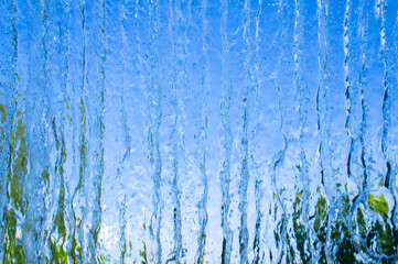 The texture of a transparent water wall from jets of water flows down. Close-up view