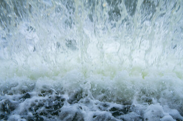 Bubbling stream of water with white foam under the waterfall