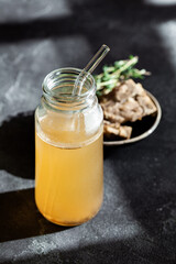 Fresh vegetable bone broth in glass jar with straw on dark gray background. Healthy dieting food are rich in vitamins, collagen and anti-inflammatory amino acids
