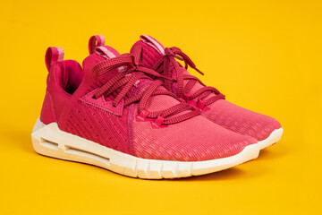 Pair of new pink sneakers, sport shoes on yellow background. Pink womens sport, running shoes