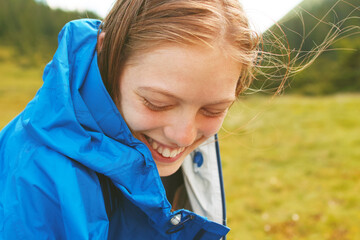 Young blonde woman laughing while sitting on the grass in the mountains © Myshkovskyi