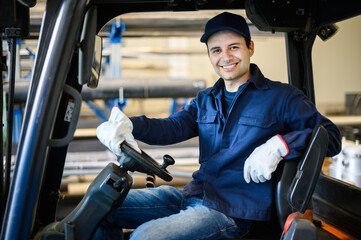 A handsome construction worker driving a forklift in an industrial plant