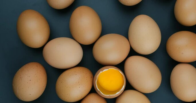Rotate shot of the raw chicken eggs with yolk on black background