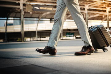 Low Section of Passenger Businessman Walking with Suitcase at the Entrance Walkway in Airport. Focus on Luggage. Low Angle View