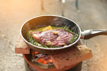 Tasty Beef steaks grill by using butter instead the oil on the pan above charcoal stove with herb ingredient