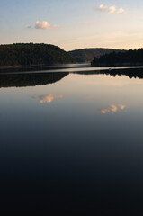 Fototapeta premium sunset over calm lake. mirroring clouds. Rappbodetalsperre, Harz, Germany